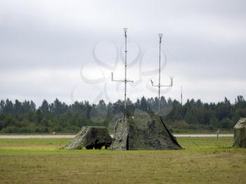 Military tent with radio and antenna camouflage net.