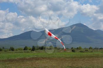 Frayed windsock in moderate wind on the background of mountains.