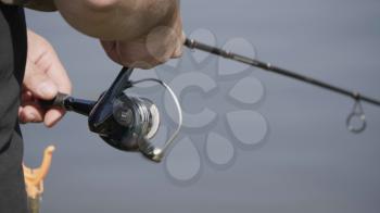 Male hand holding fishing rod and reeling the other hand.