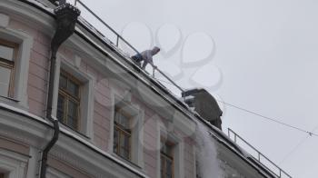 MOSCOW - DECEMBER 20, 2018: Cleaning roofs of buildings from snow, ice in the winter with a shovel December 20, 2018 in Moscow, Russia.