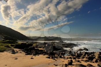 Picture of Black Rocks and White Cloads in Blue Sky at Beach