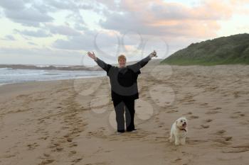 Happy Holiday Woman with Arms Raised on Beach with Dog