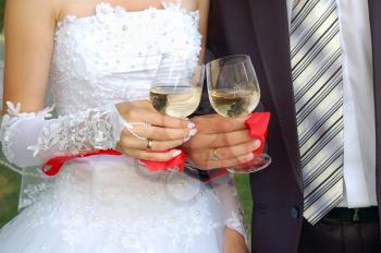 two glasses with champagne in the hands of groom and fiancee