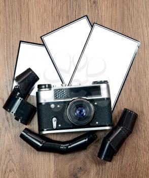 old retro photo camera and blank photo on wooden background