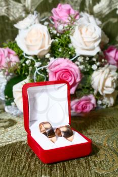 two wedding rings in red box and flowers