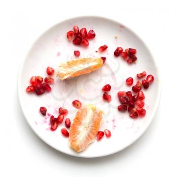 Pomegranate with an orange on a plate on a white background