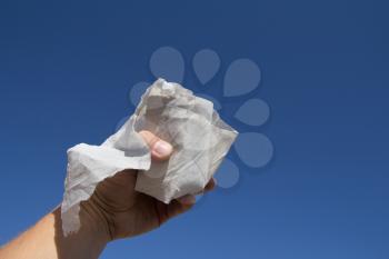 toilet paper in the man's hand on a background of blue sky