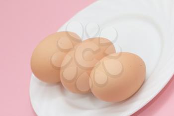 fresh eggs on a plate on pink background