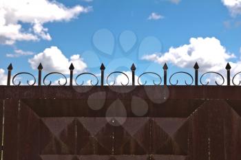 iron fence and a blue sky with clouds
