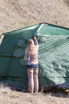 Girl puts a tent on the nature
