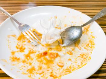Dirty white plate with eaten food in a cafe .