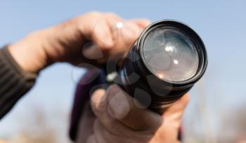 A large lens in the camera of a man .