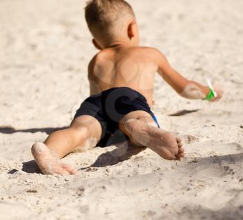 Feet of a boy playing in the sand .