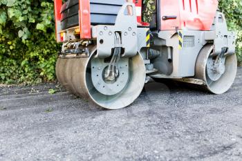 heavy machine rolls a new asphalt road .