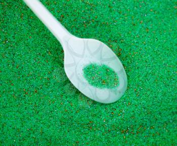 green colored sand with a spoon as a background .