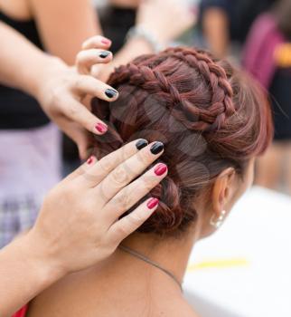 the stylist weaves the female braids on the head .
