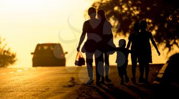 family walking on the road at sunset .