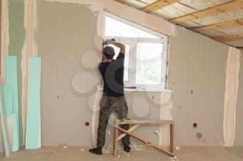 The worker works with plastic for windows in the house .