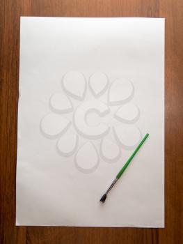 white sheet of paper with a brush on a wooden background