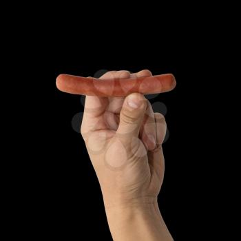Sausage in a hand on a black background