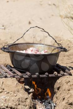 meat with potatoes in a cauldron on fire