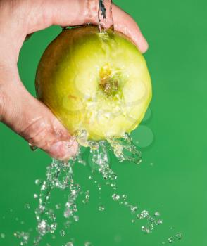 apple in his hand in the water on a green background