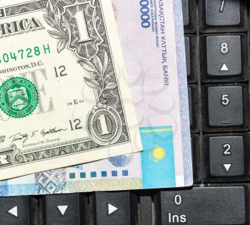Kazakh tenge and dollars on a laptop keyboard