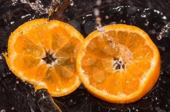 Orange in water splashes on a black background