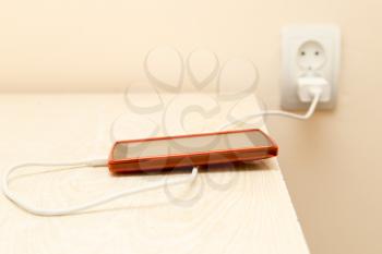 cell phone is being charged from the electrical outlet