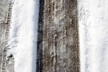 trace of the car in the snow with asphalt