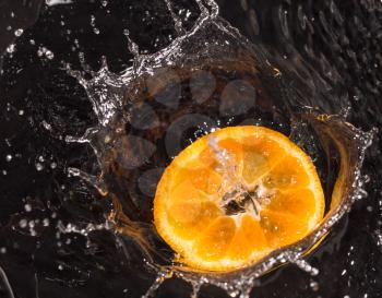 Orange in water splashes on a black background