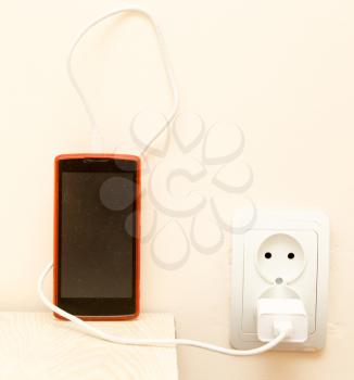 cell phone is being charged from the electrical outlet