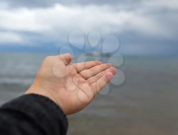 man's hand on a background of the sea with clouds