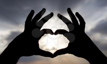 Silhouette of hands in form of heart on the background of sunset