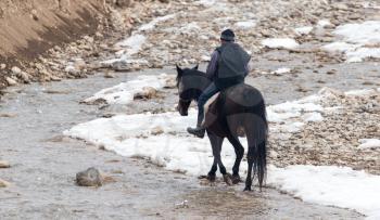 Rider on the horse on the river in winter