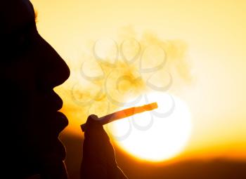 Silhouette of male smokers in the sunset