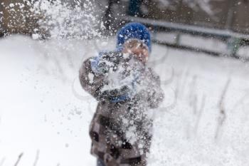 Boy playing with snow in winter