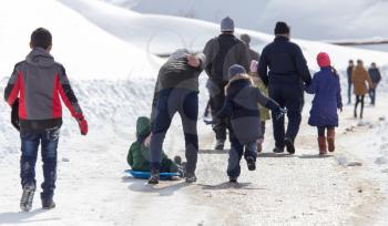 Dad and children ride baby on sled