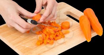 cook cuts carrots on a board on a black background .