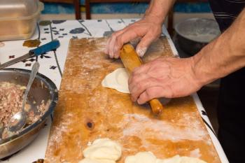 man prepares dumplings at home . Cooking food
