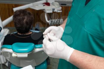A dentist prepares an implant in the clinic .