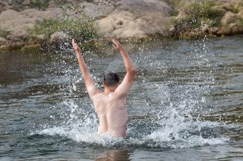 a man jumps out of the water .