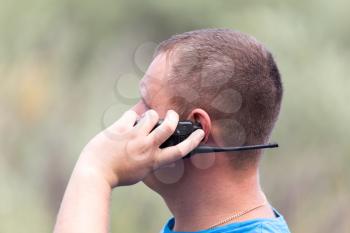 a man with a walkie-talkie outdoors . A photo