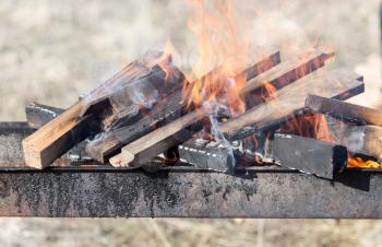 Firewood is burning in the grill in the open air