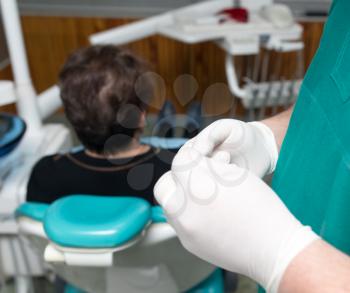 A dentist prepares an implant in the clinic .