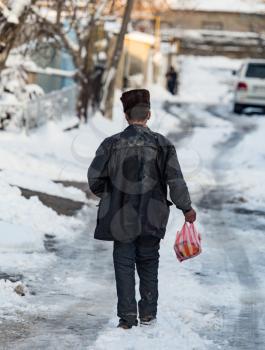 Homeless man is walking on the road in winter .