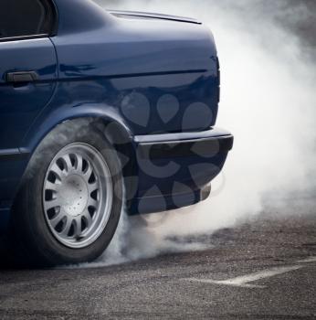 Smoke from under the wheels of the car .