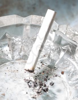 A white cigarette lies in an ashtray .