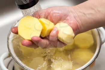 The cook washes the peeled potatoes in the water .