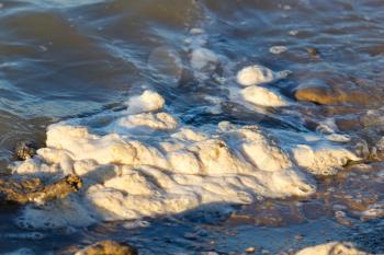 Foam on the shore of the reservoir as a background .
